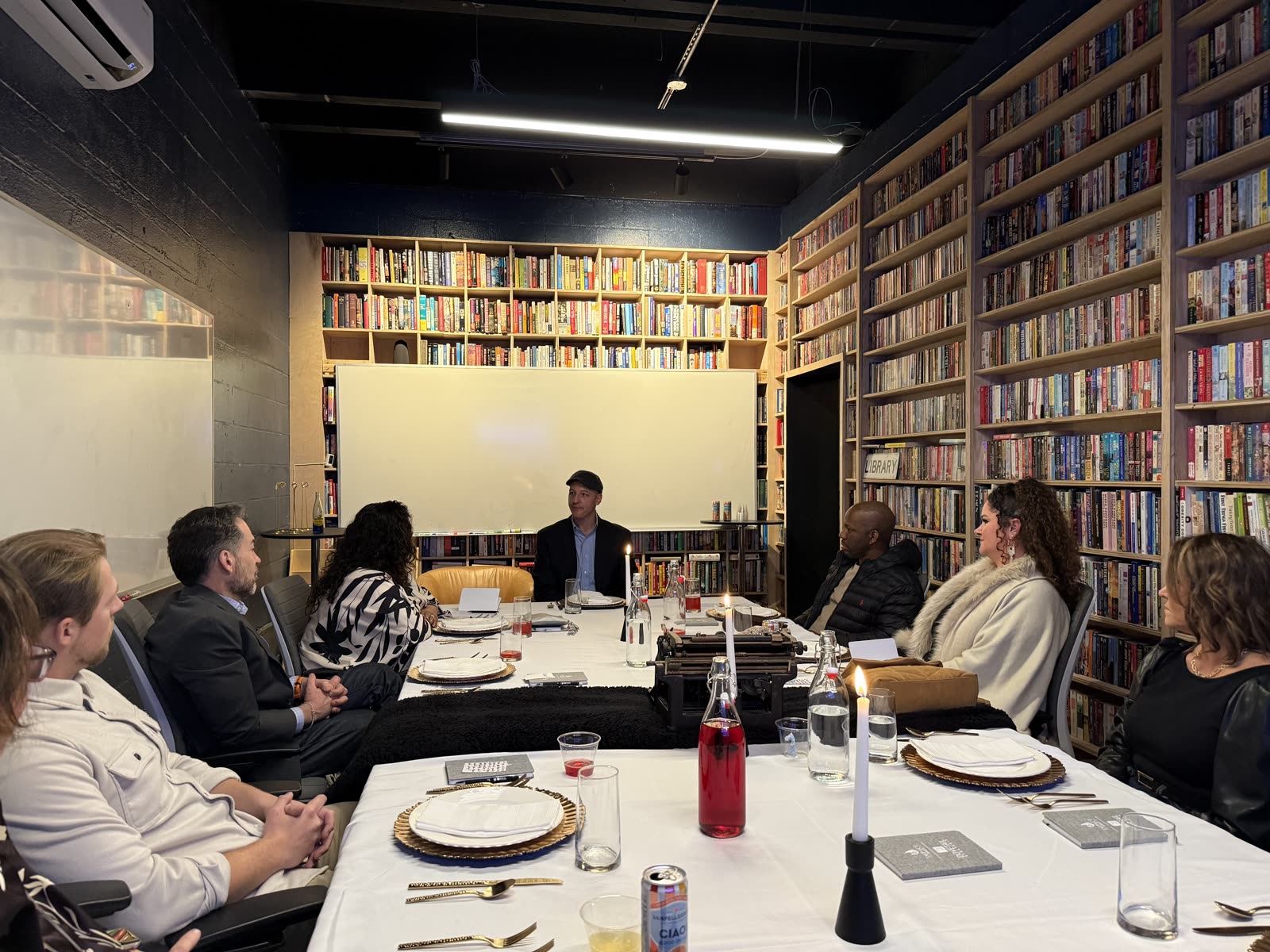 Attendees seated around a long table in a library for an intimate Connect or Die dinner