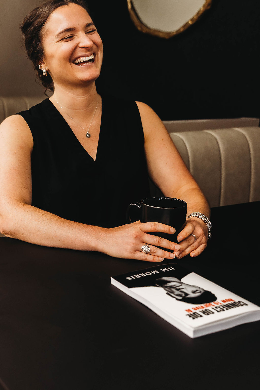 Reader laughing over coffee with a copy of Connect or Die on the table